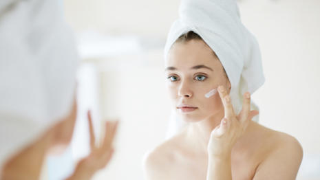 Žena s uterákom na hlave aplikujúcim krém Bepanthen DERMA